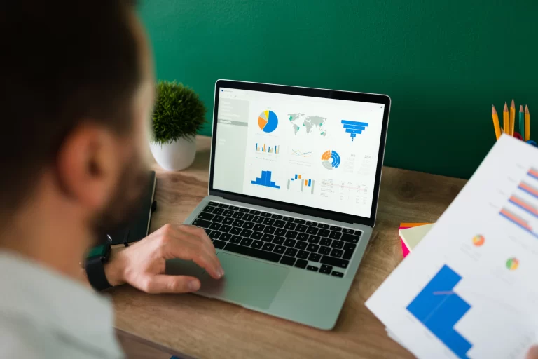 rear-view-young-man-working-his-laptop-looking-work-report-graphs